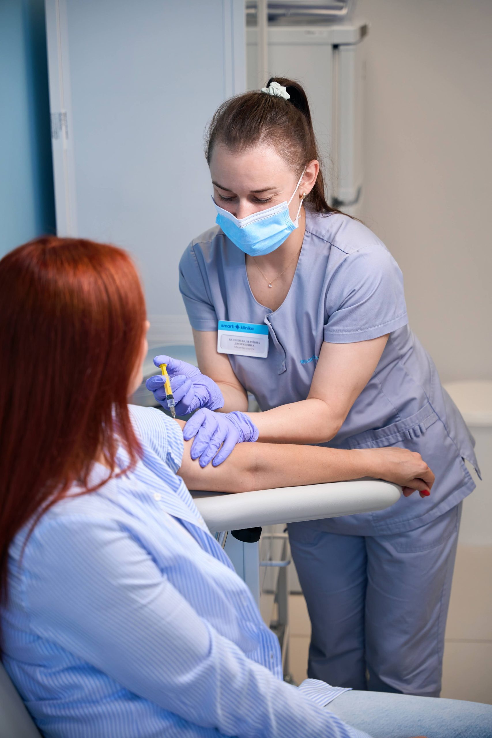 Медична сестра проводить вакцинацію пацієнтці в маніпуляційній